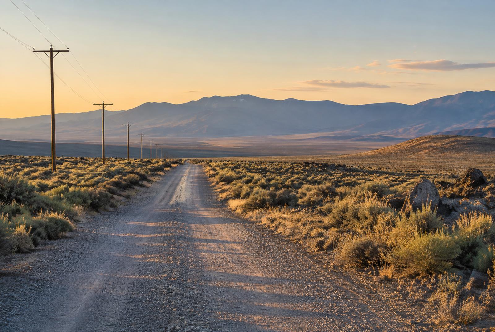 Gravel road crossing Northern Nevada acreage at golden hour